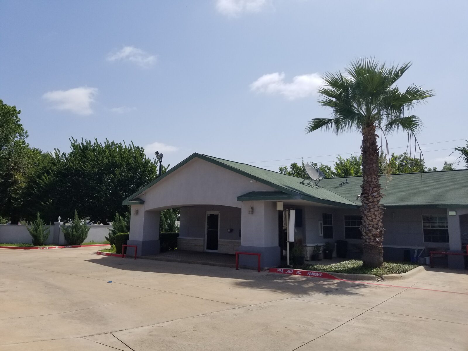 Haltom Inn front office and check-in entrance with covered carport and palm tree — Haltom City, Texas